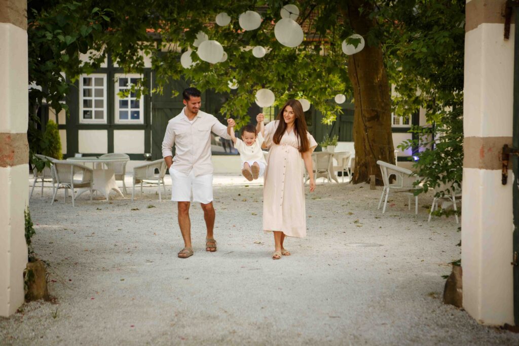 Mama und Papa schwingen ihren Sohn spielerisch in die Luft