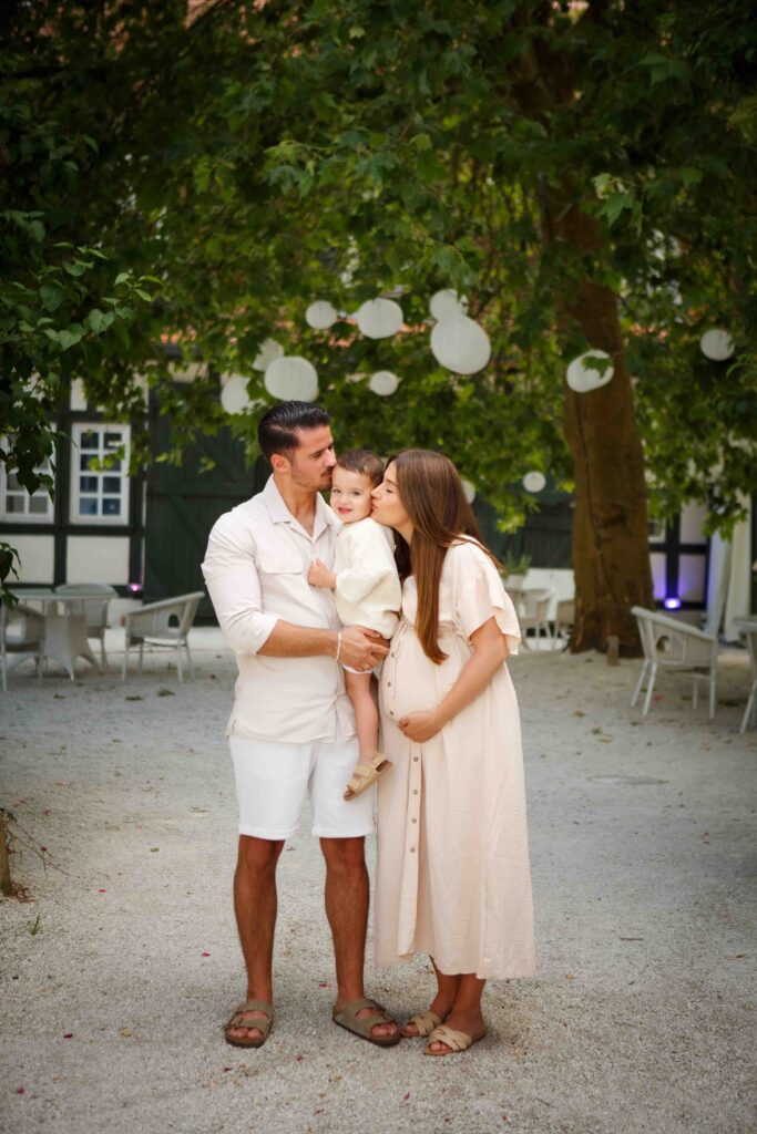 Eltern küssen ihren Sohn gleichzeitig, das Kind lacht fröhlich