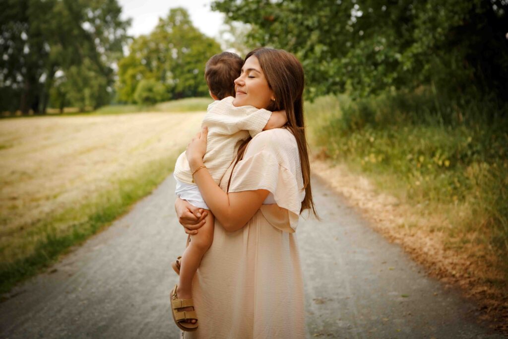 Mama mit Babybauch steht und umarmt ihren Sohn glücklich