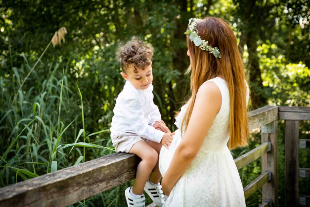 Kind berührt neugierig den Babybauch seiner Mama