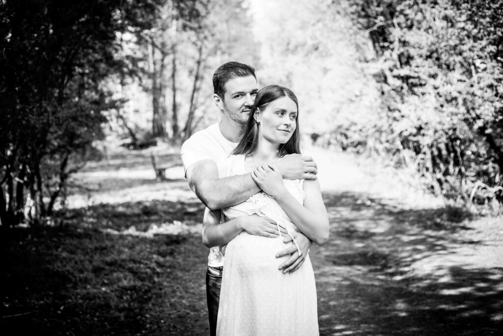 Paar in inniger Umarmung, der Mann hält seine schwangere Frau von hinten fest