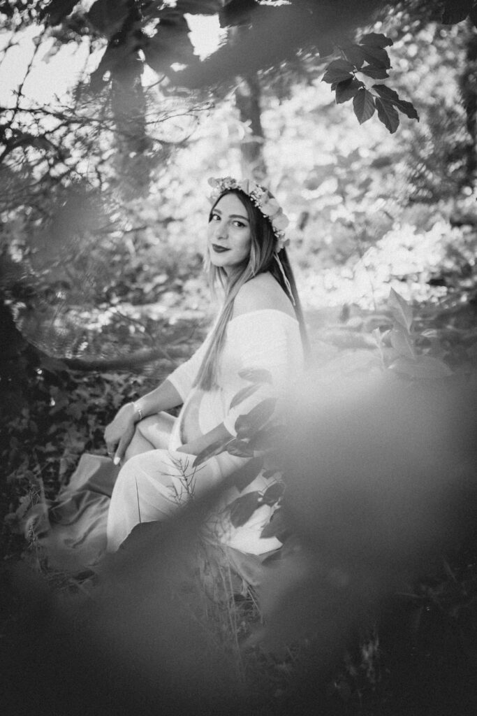 Frau mit Babybauch und zartem Blumenkranz im Haar