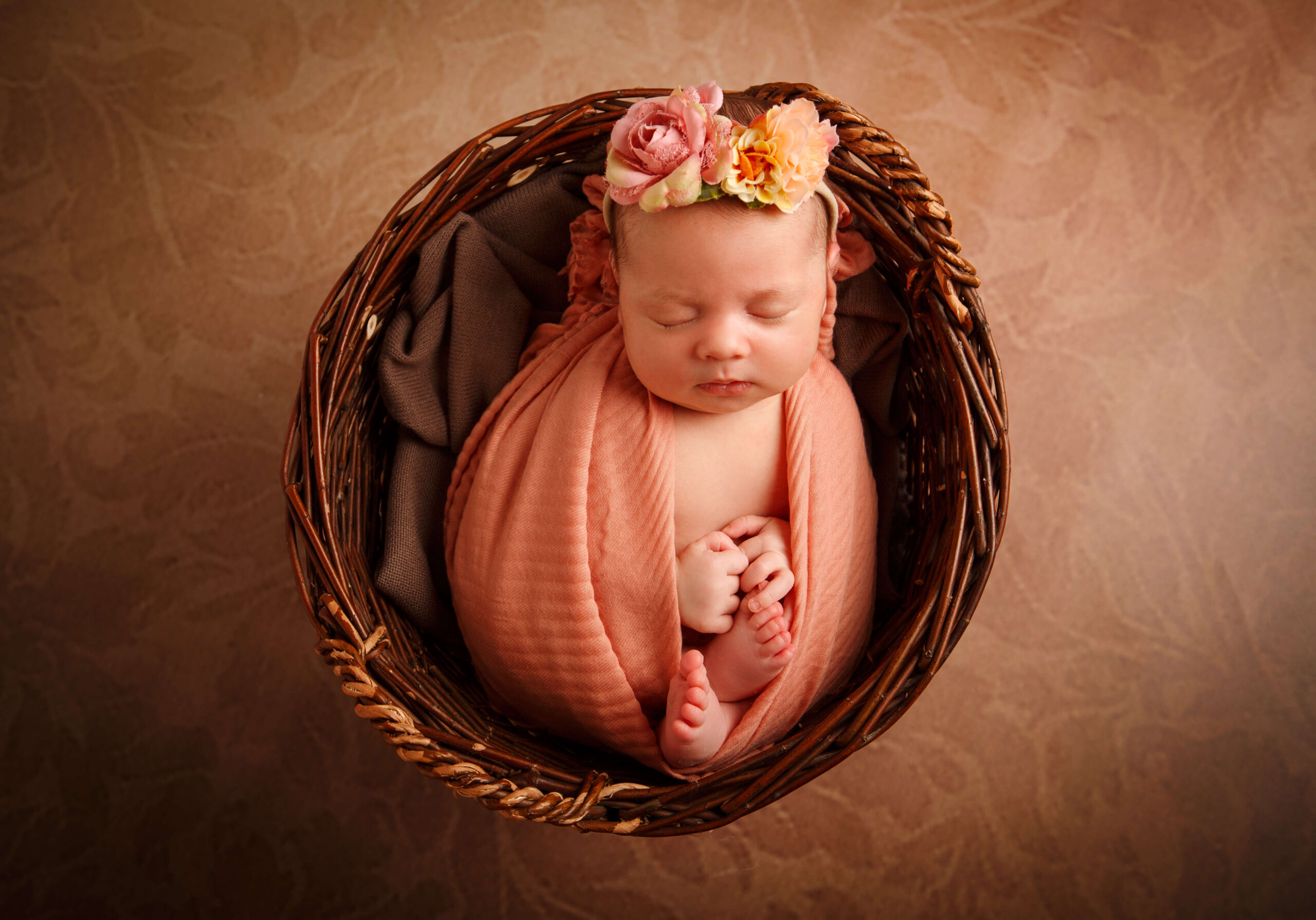 Neugeborenes liegt entspannt in einem runden Korb, fotografiert von oben