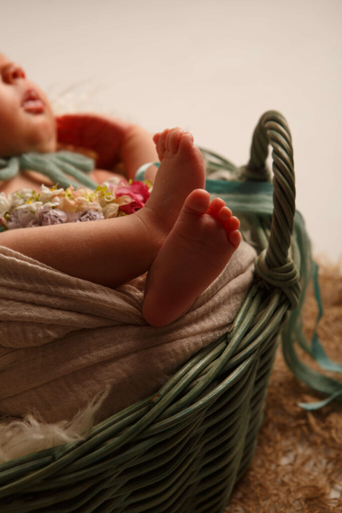 Kleine Babyfüße schauen aus einem geflochtenen Korb hervor