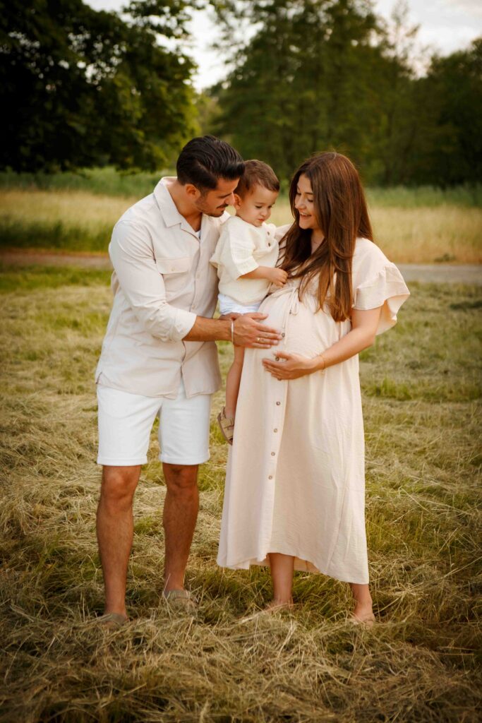 Schwangere Frau steht, während der Papa sanft ihren Babybauch streichelt