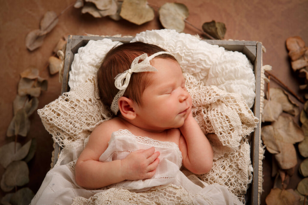 Neugeborenes liegt niedlich und geborgen in einer Holzkiste.