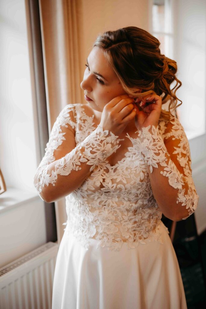 Braut zieht Ohrringe für die Hochzeit an