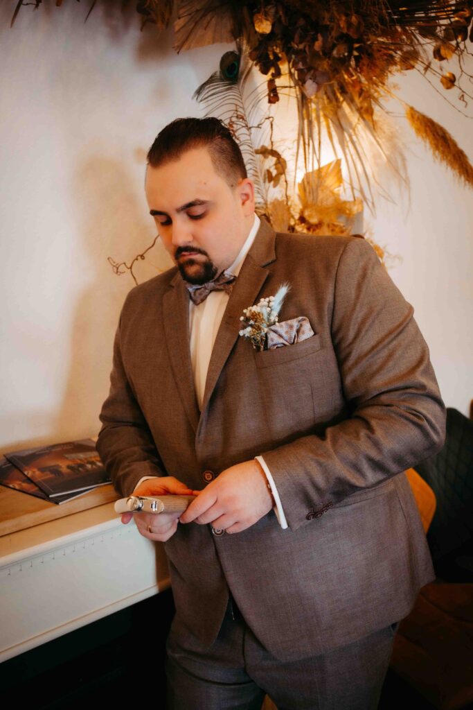 Bräutigam hält Flachmann in der Hand und blickt darauf