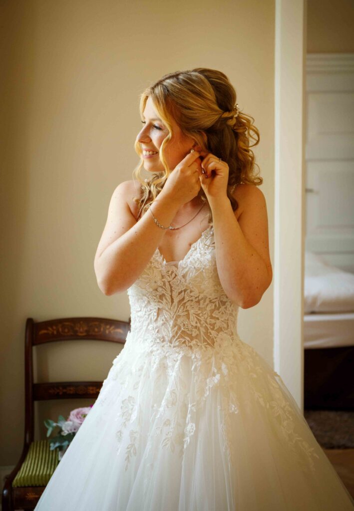 Getting-Ready: Braut steckt Ohrring im Schloss an