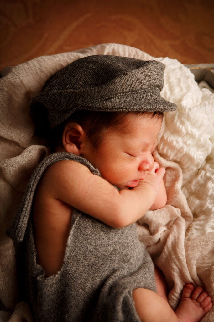 Neugeborenes liegt gemütlich auf einer weichen Decke und trägt eine niedliche Mütze