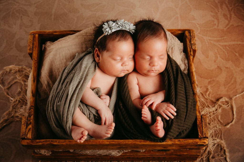 Zwillingsbabys liegen friedlich nebeneinander in einer Holzkiste