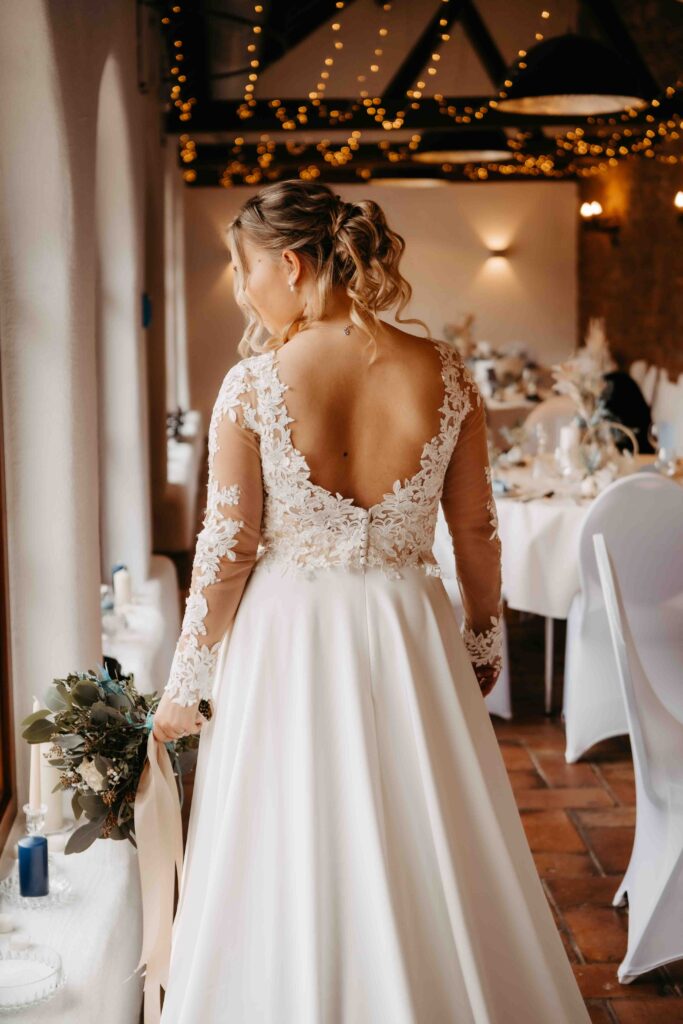 Braut steht mit dem Rücken zur Kamera im Kleid