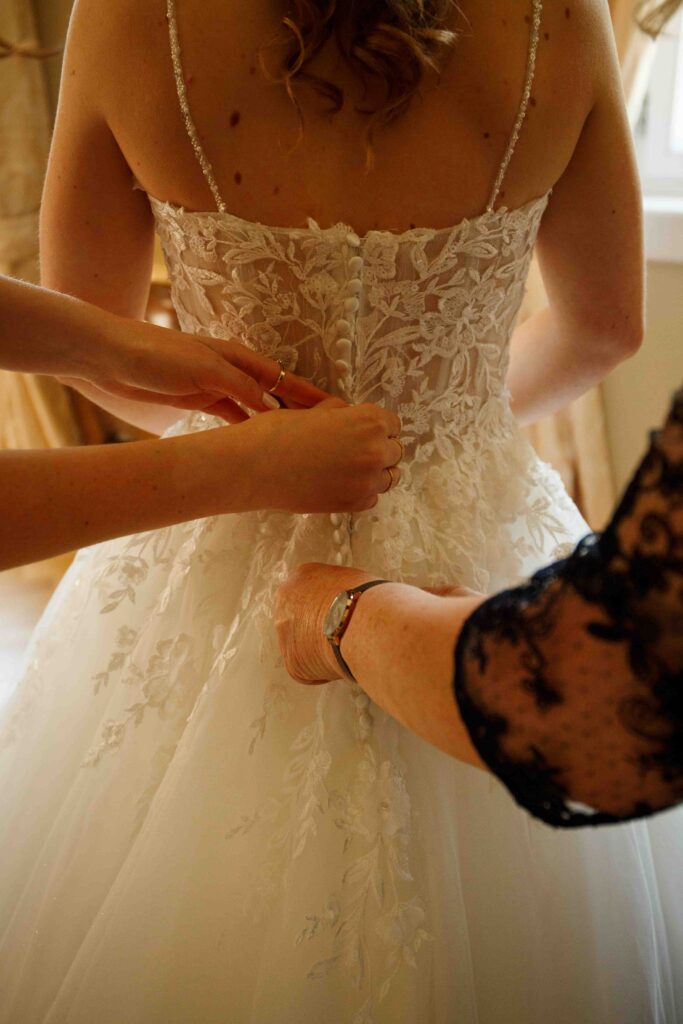Mama und Trauzeugin richten das Brautkleid der Braut
