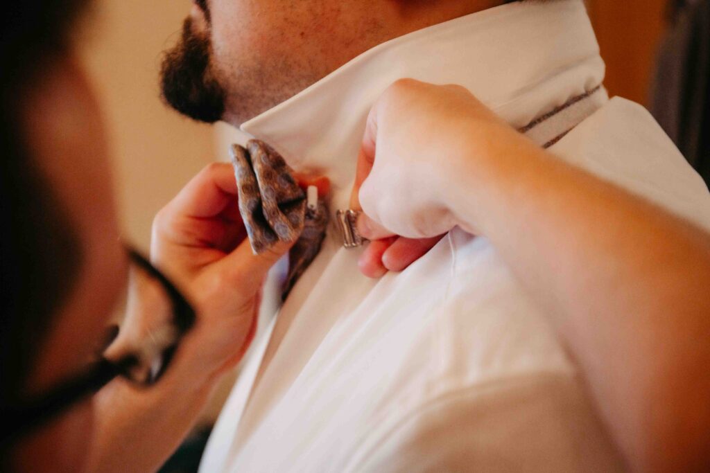 Detailaufnahme: Hände binden die Fliege des Bräutigams