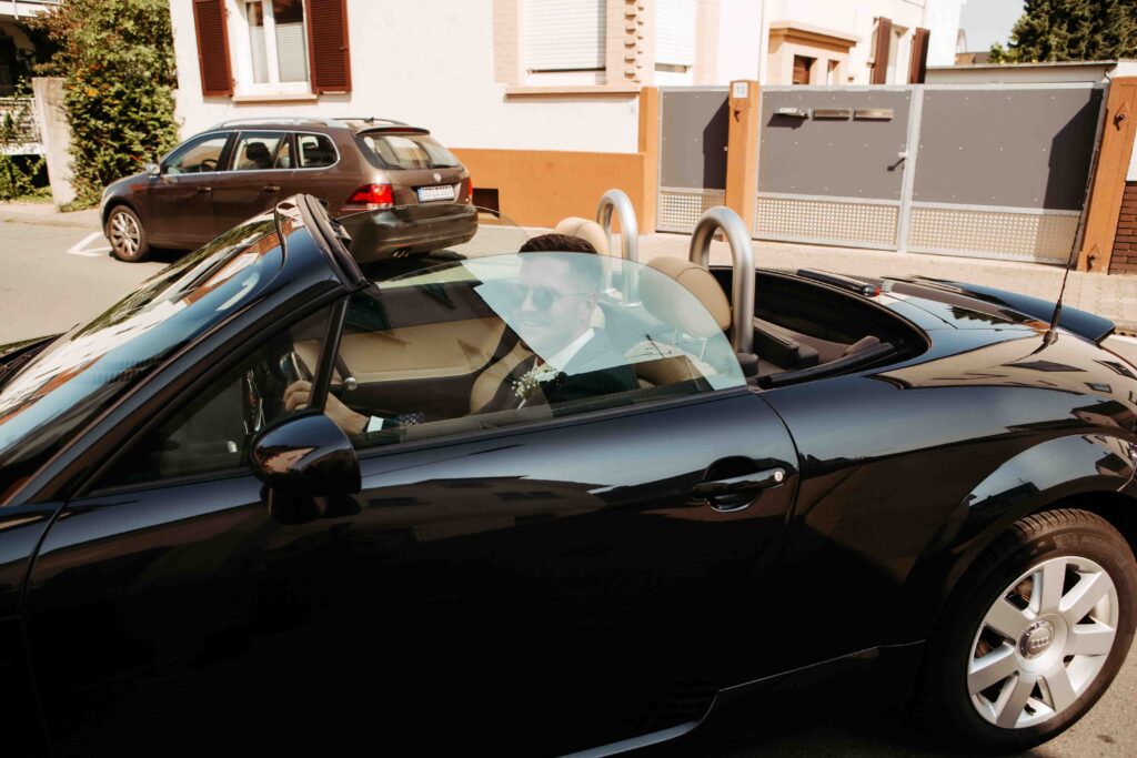 Bräutigam kommt mit schwarzem Auto zur Hochzeit