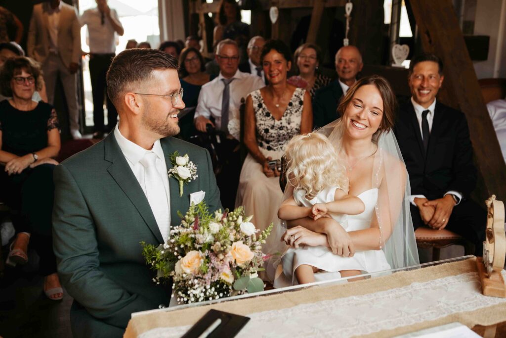 Familienmoment: Brautpaar und Tochter vor dem Standesamt