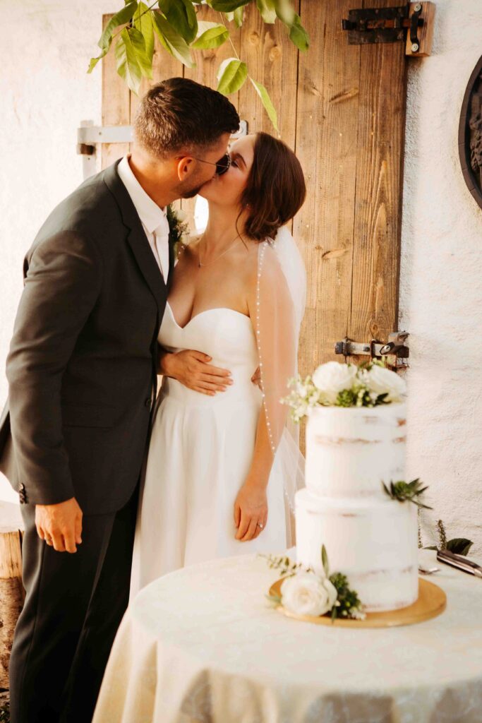 Brautpaar küsst sich, Hochzeitstorte im Vordergrund