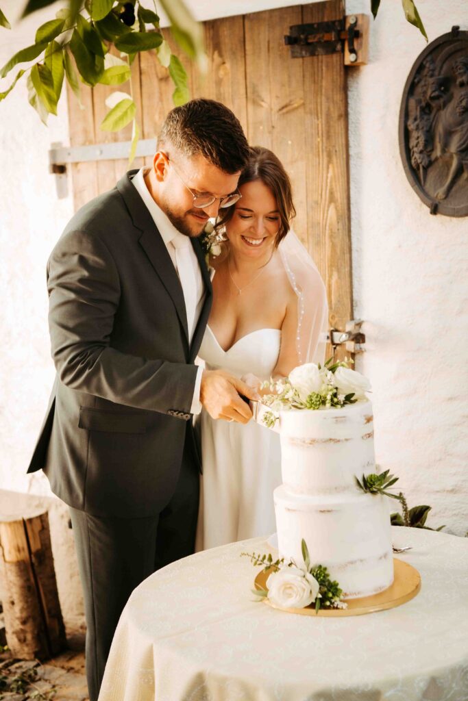 Erster Schnitt in die Hochzeitstorte durch Braut und Bräutigam