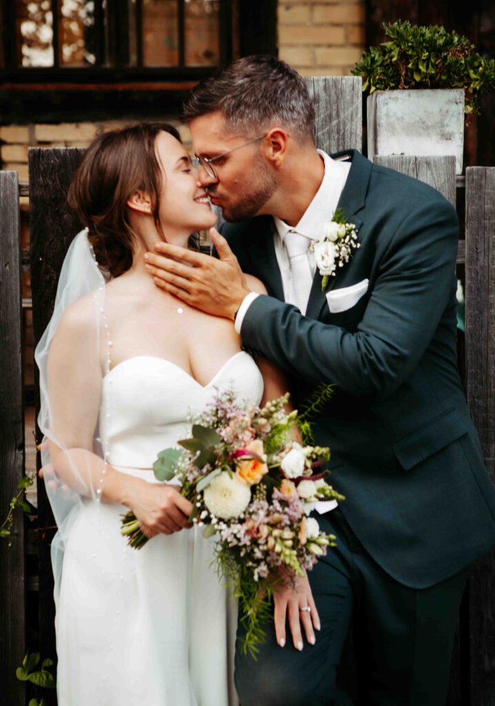 Braut und Bräutigam beim Fotoshooting am Holzzaun