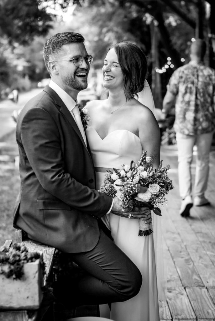 Herzhaftes Lachen von Braut und Bräutigam beim Fotoshooting