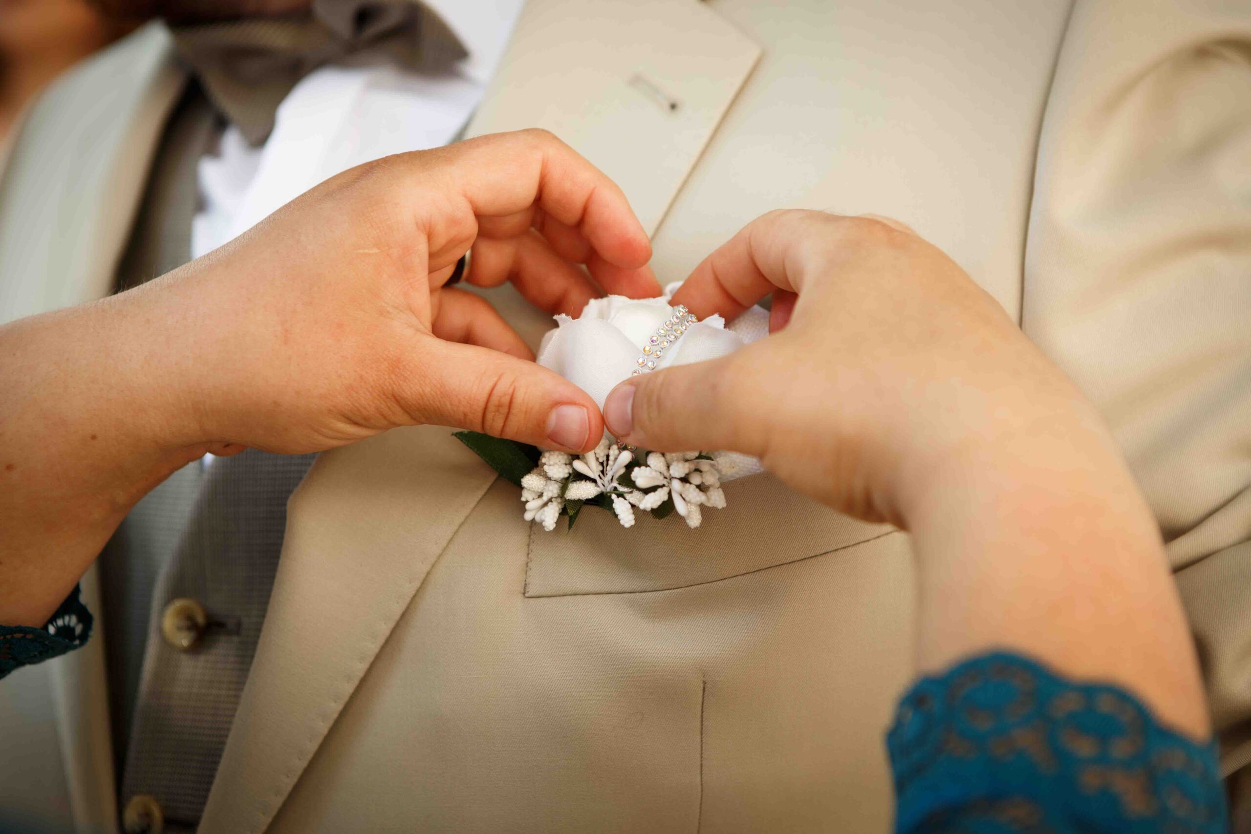 Detailaufnahme: Blumenanstecker des Bräutigams wird zurechtgemacht