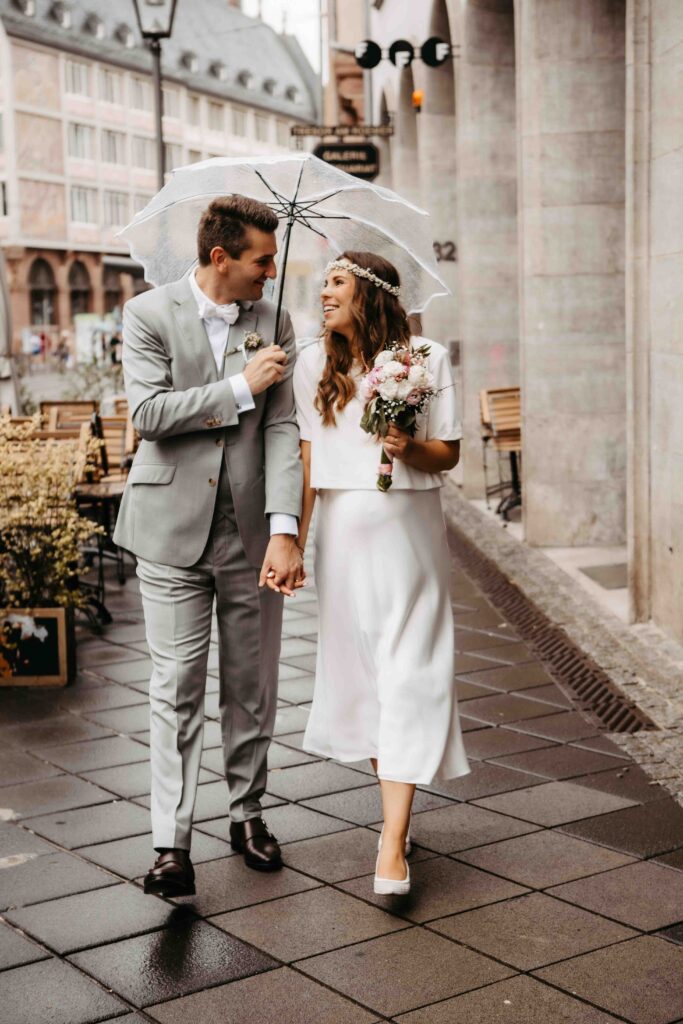 Brautpaar läuft mit Regenschirm durch Frankfurt