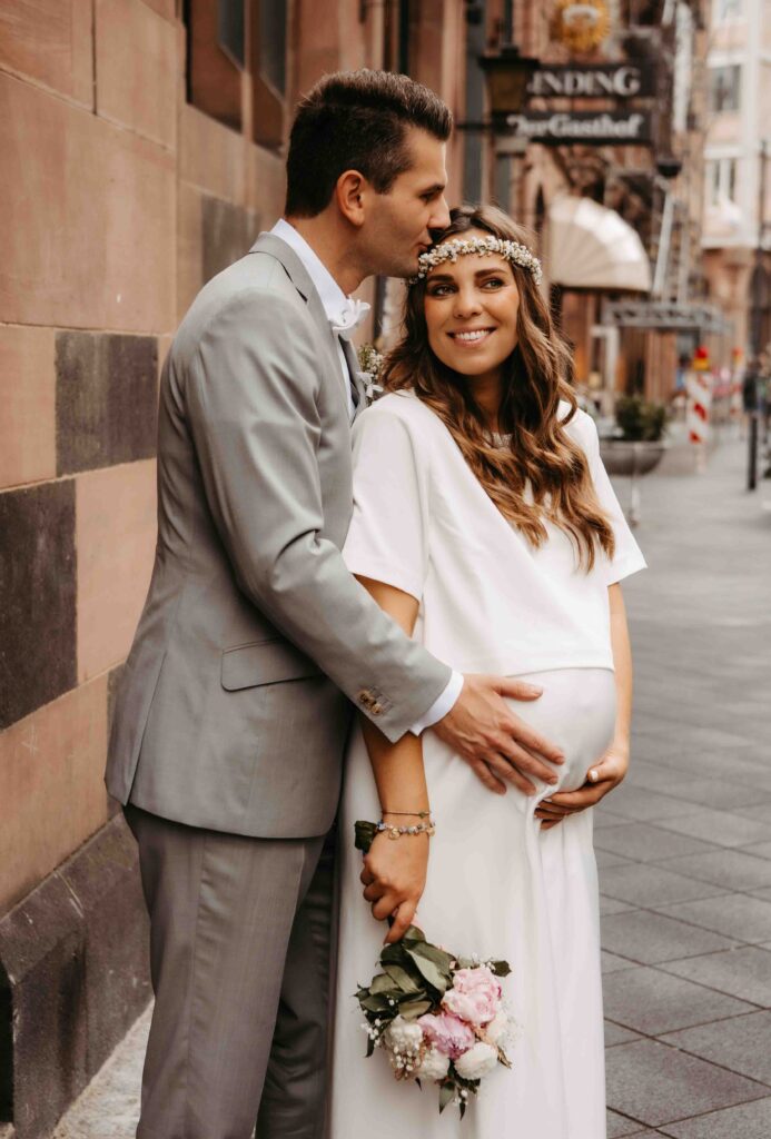 Bräutigam hält den Babybauch der Braut beim Shooting