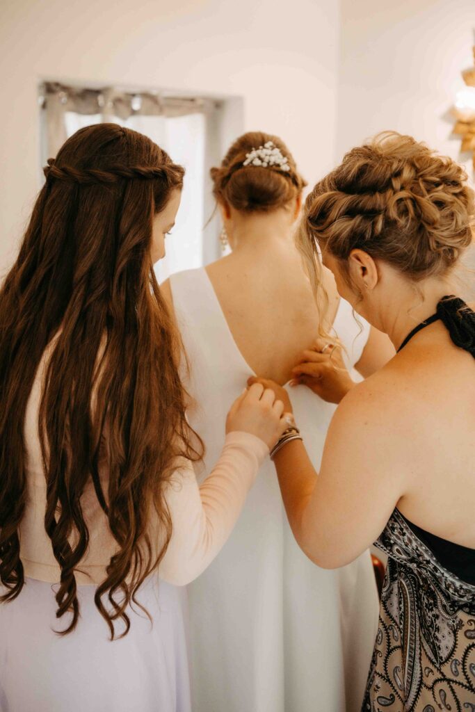 Die Braut bekommt das Kleid geschloßen, Tochter hilft.