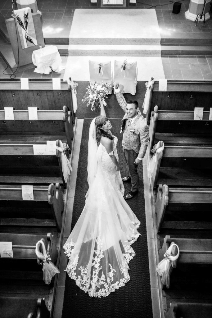 Brautpaar wurde von oben in der Kirche fotografiert, die Hände gehen nach oben.