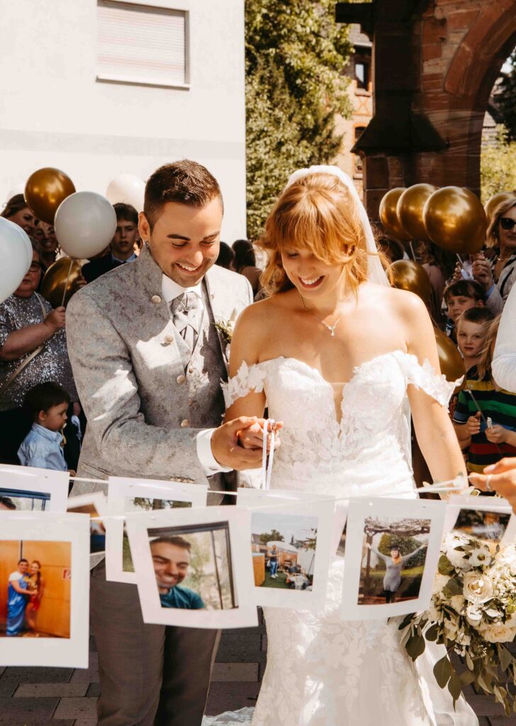 Brautpaar schneidet band durch es hängen Bilder daran